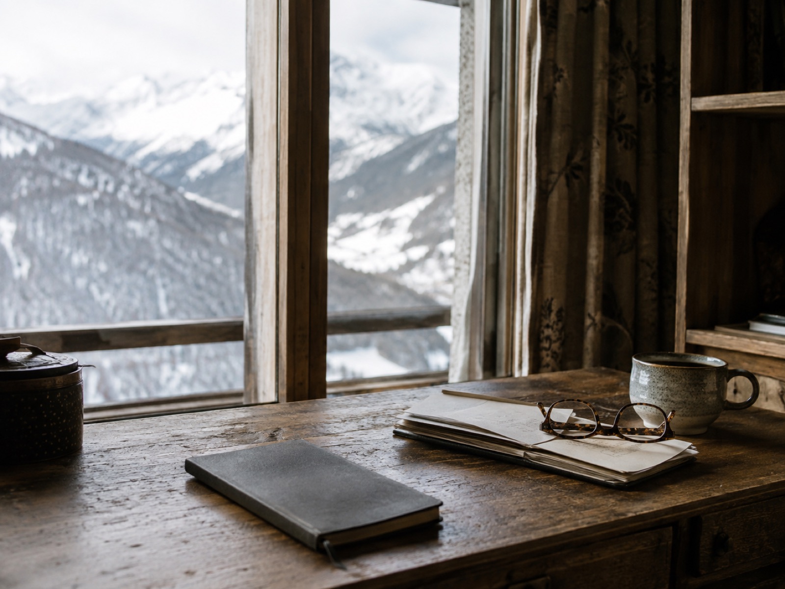 Schreibtisch am Fenster mit geordneten Unterlagen, Bergblick